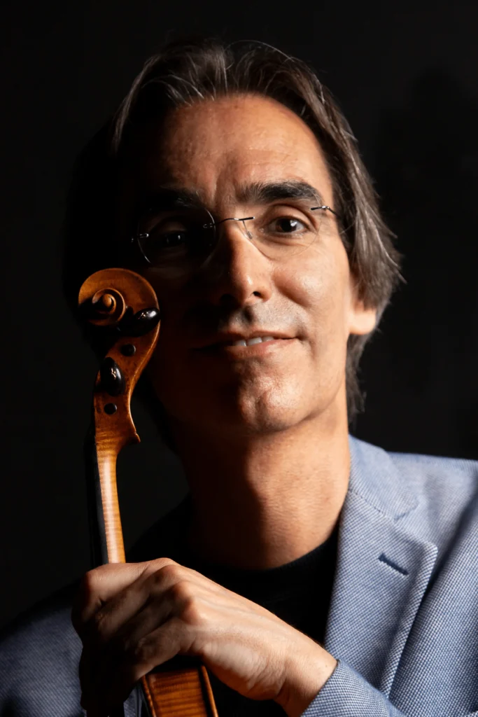 Carlos Damas smiling and holding a violin
